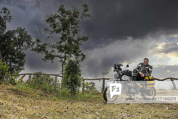 Ein Mann posiert auf seinem Geländemotorrad vom Typ Scrambler in Thailand
