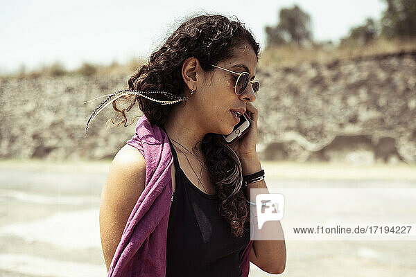 Mexikanische junge trendige Frau am Telefon in trockener Natur