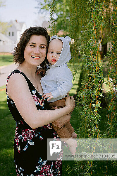 Mother and infant son smiling and playing in front yard in spring