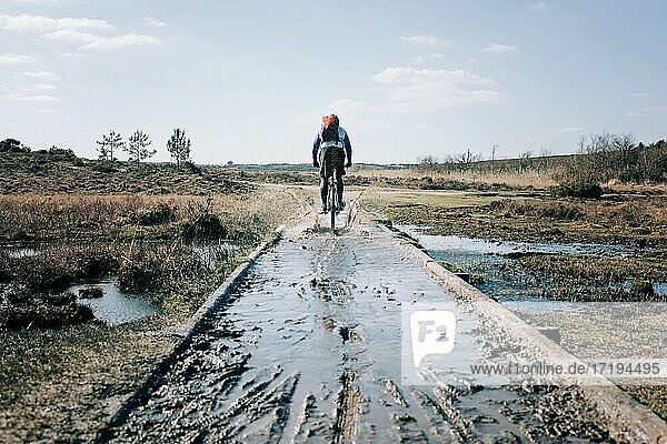 man riding through a muddy puddle whilst mountain biking in England