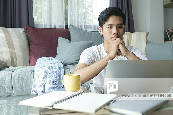 Junger Mann arbeitet und lernt online zu Hause.