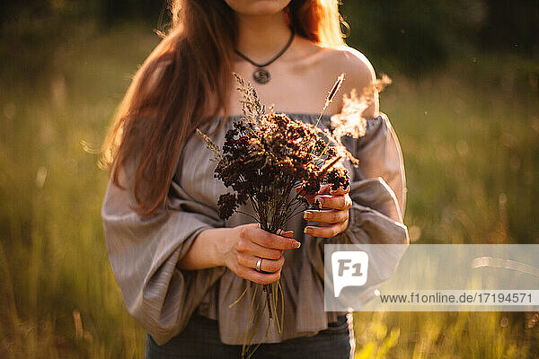 Nahaufnahme einer Frau mit einem Strauß getrockneter Blumen im Sommer