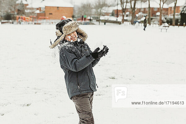 Boy being hit in face by snowball with snow covered houses behind