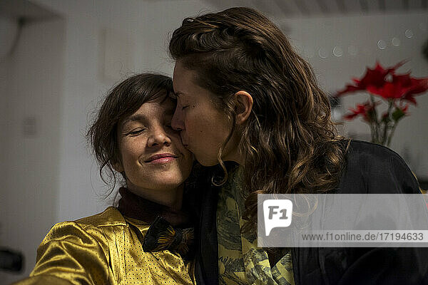 schwules lesbisches Paar kuschelt und lächelt zu Hause während einer Dinnerparty