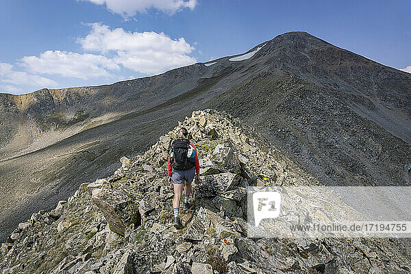 Rückansicht einer Wanderin  die auf Felsen am Berg läuft