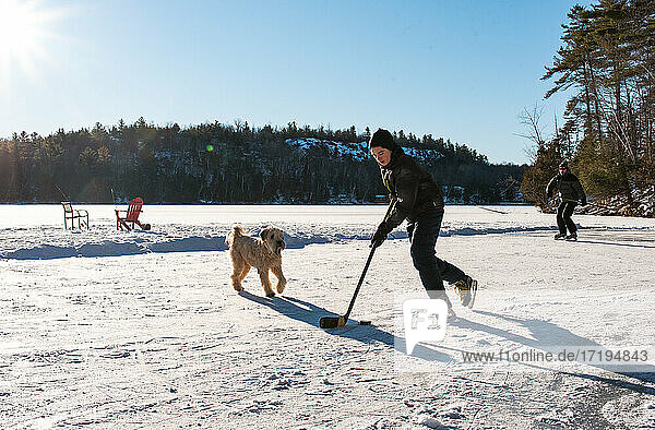Vater und Sohn spielen Hockey auf einer Eisbahn auf einem zugefrorenen kanadischen See.