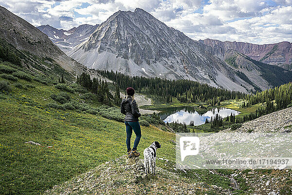 Female hiker with dog looking at beautiful mountain