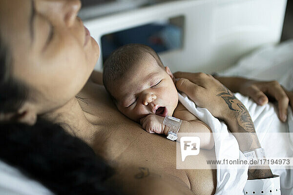 Ein Neugeborenes mit seiner jungen Mutter im Krankenhaus  das sich ausruht.