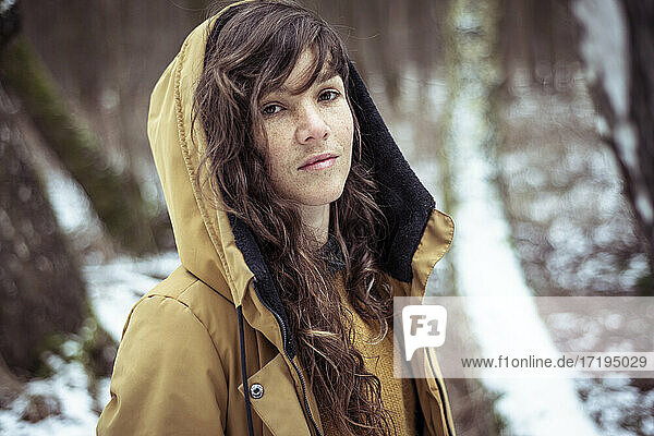 Junge Frau mit Sommersprossen und langen lockigen Haaren in winterlicher Schneejacke