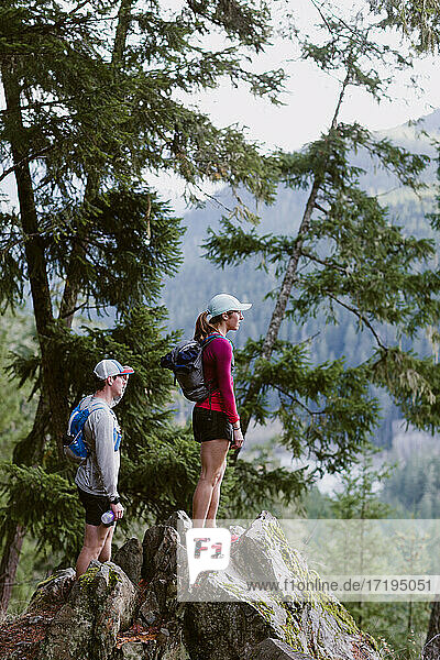 Female and male trail runners stop to take in the view of mountains