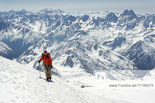 Mann mit Skistock beim Besteigen eines schneebedeckten Berges im Urlaub