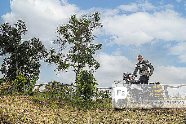 Man posing on his scrambler type off road motorcycle in Thailand