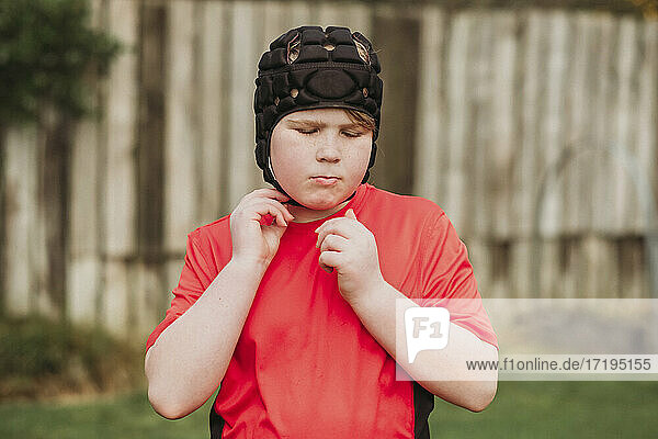 Junge zieht im Hinterhof Rugby-Schutzkleidung an