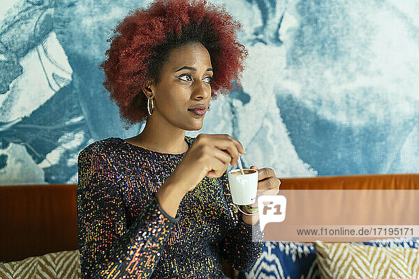 schöne Frau mit Afro-Haar trinkt einen Kaffee