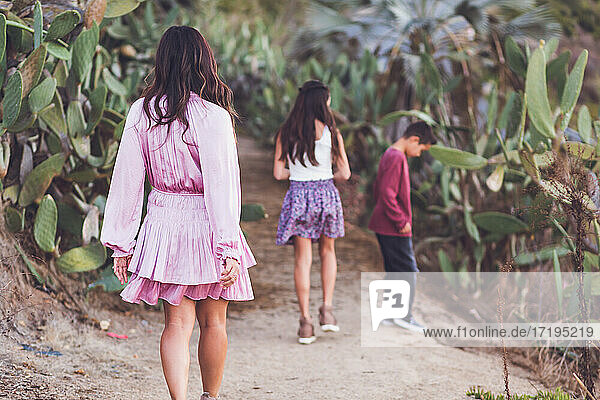 Mutter geht mit Tochter und Sohn auf einem Kaktusweg spazieren.
