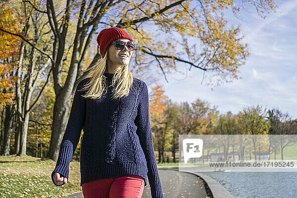 Junge Frau in modischer Kleidung geht im Park spazieren