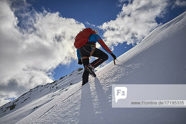 Man climbing a snowy mountain on a sunny day in Devero  Italy.