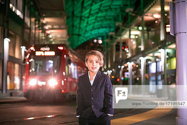 Boy wearing suit standing at train station in Downtown.