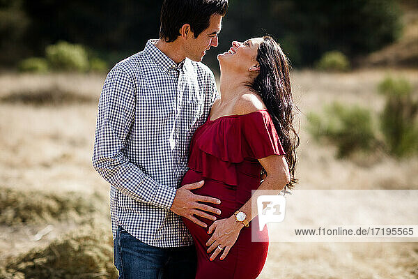 Ehemann und schwangere Frau posieren auf einem Feld in San Diego