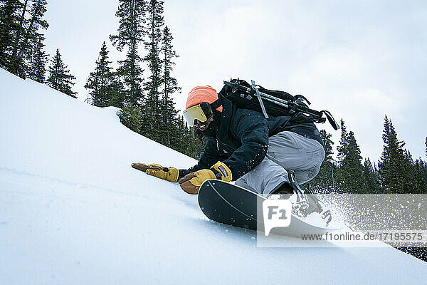 Mann Snowboarding auf schneebedeckten Berg gegen Himmel im Urlaub