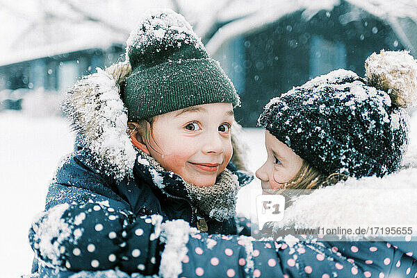 Two children hugging in snow and playing together in nor'easter storm