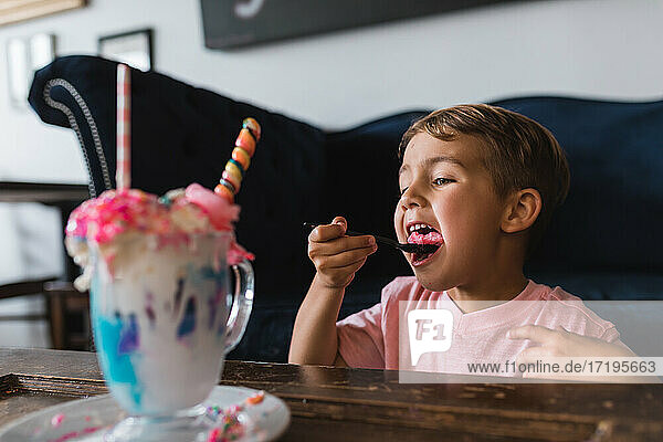 Ein Junge beißt in eine Süßigkeit aus einem bunten Milchshake.