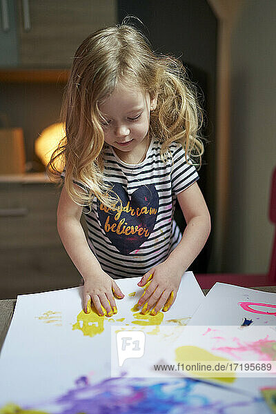 Nettes kleines Mädchen Künstlerin mit gelben gemalten Palmen Zeichnung auf weißem Blatt Papier.