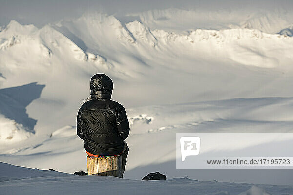 Rückansicht eines Mannes mit Blick auf die Aussicht von einem schneebedeckten Berg