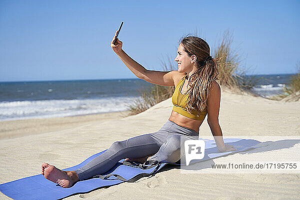 Mädchen  das ein Selfie macht  während es am Strand Yoga übt.