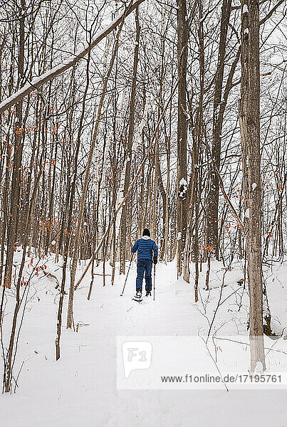 Teen boy snowshoeing alone in the woods on a snowy winter day.