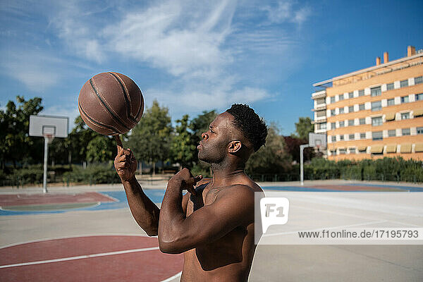 Ernster afroamerikanischer Mann macht Trick mit Basketball
