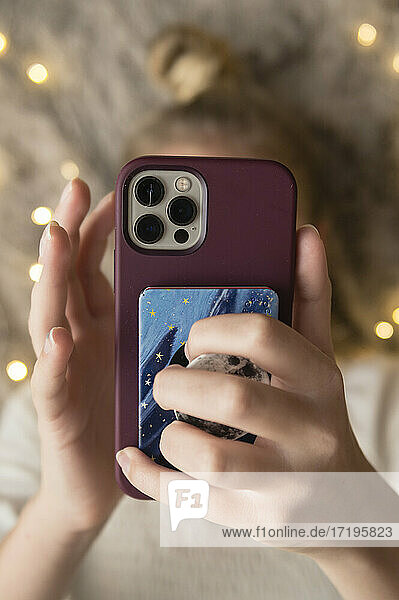 Close-Up of Teen/Tween Girl Holding Mobile Phone Illuminated by Lights