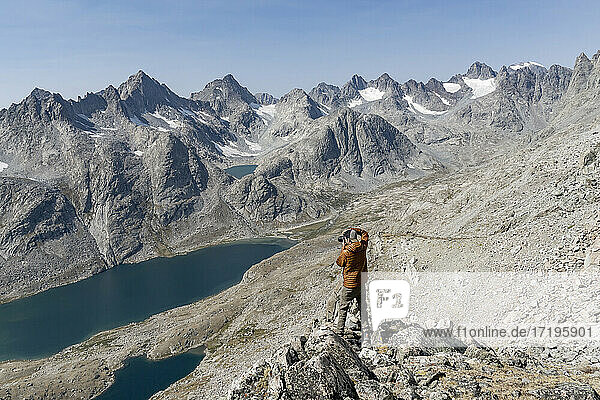 Rückansicht eines Mannes beim Fotografieren von Bergen während einer Wanderung im Urlaub