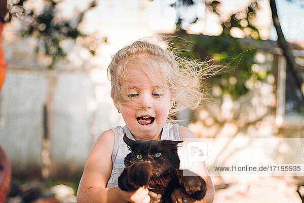happy little girl playing with kitten