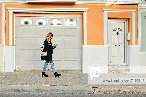 Woman walks while she is looking at her smartphone on the street