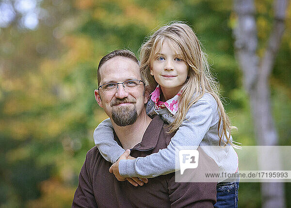 Father with young blond daughter hugging.