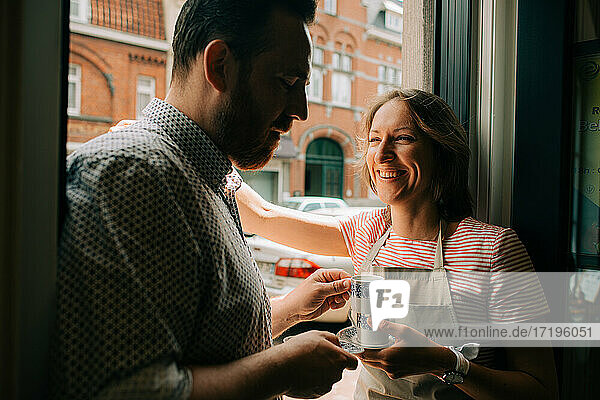Married couple standing at the entrance with cups of coffee  smiling