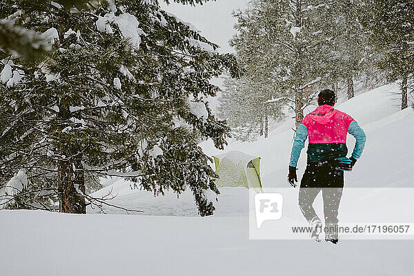 Ein Mann in heller Jacke geht durch tiefen Schnee aus seinem Zelt