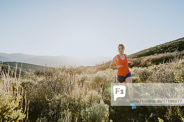 Athletic blonde woman trail runs in the mountains at golden hour