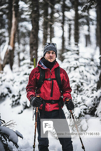 portrait of male skier with red jacket in snow covered woods in Maine
