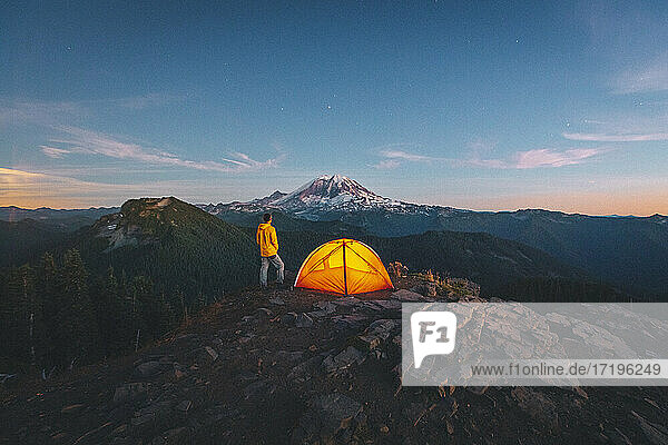 Ein Mann steht bei einem Zelt auf dem Gipfel eines Berges in der Nähe des Mount Rainier. Rainier