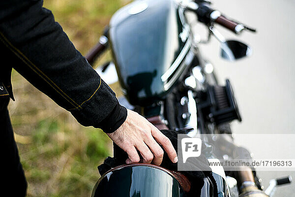 Mann nimmt Handschuhe vom Sitz eines klassischen Motorrads