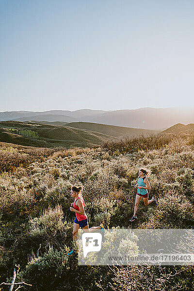 Zwei sportliche Frauen beim Trailrun in den Bergen zur goldenen Stunde