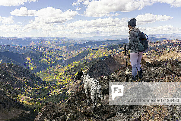 Frau wandert mit Hund auf einem Berg gegen den Himmel im Urlaub