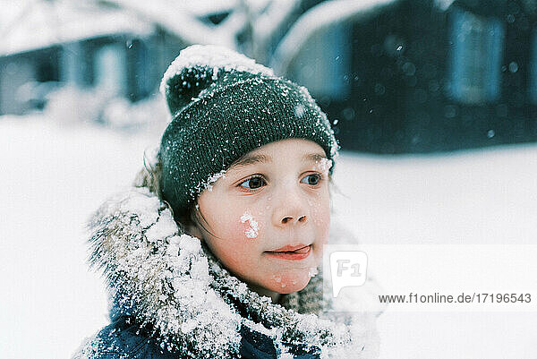 kleiner junge leckt schnee von den lippen während eines schneesturms in new england
