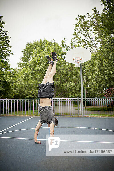 Mann macht einen Handstand auf dem Basketballplatz