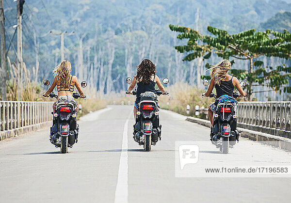 drei Freundinnen fahren Roller auf der Autobahn in Laos