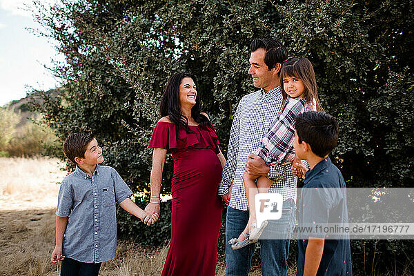 Schwangere Mutter lacht mit Familie im Feld in San Diego