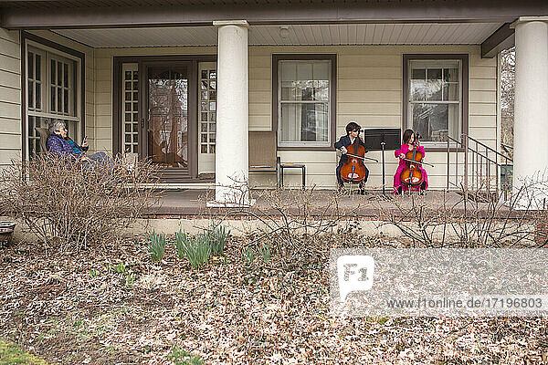 Fernblick auf zwei Kinder  die ein Cellokonzert für eine ältere Frau geben