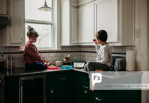 Bruder und Schwester sitzen zusammen in der Küche und essen Waffeln